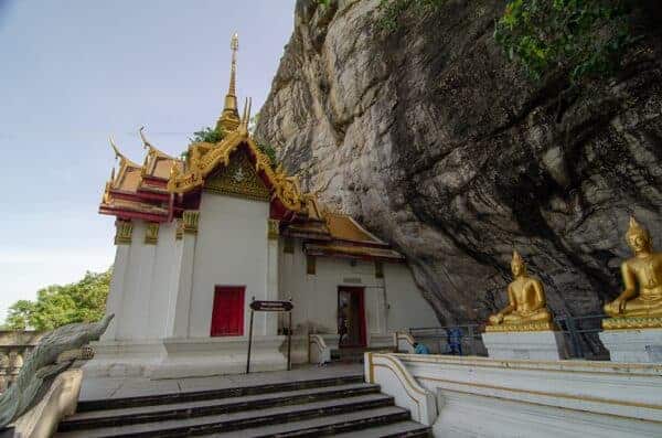 The cliff side of Wat Phraphuttachai. The rock art is located just to the right of the pavilion's entrance, behind the Buddha statues.